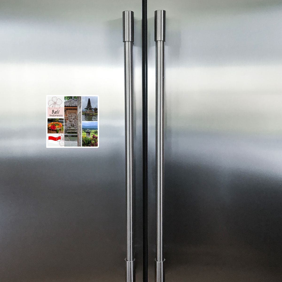 Stainless steel refrigerator with a small travel magnet on the door.