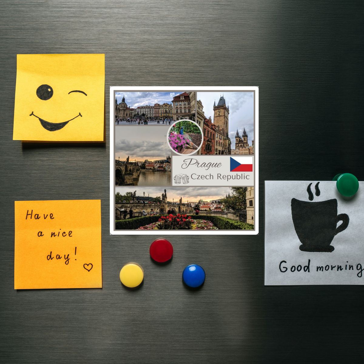 Decorative magnets on a metallic surface with a smiley face, 'Have a nice day!' note, Prague postcard, and coffee cup design.