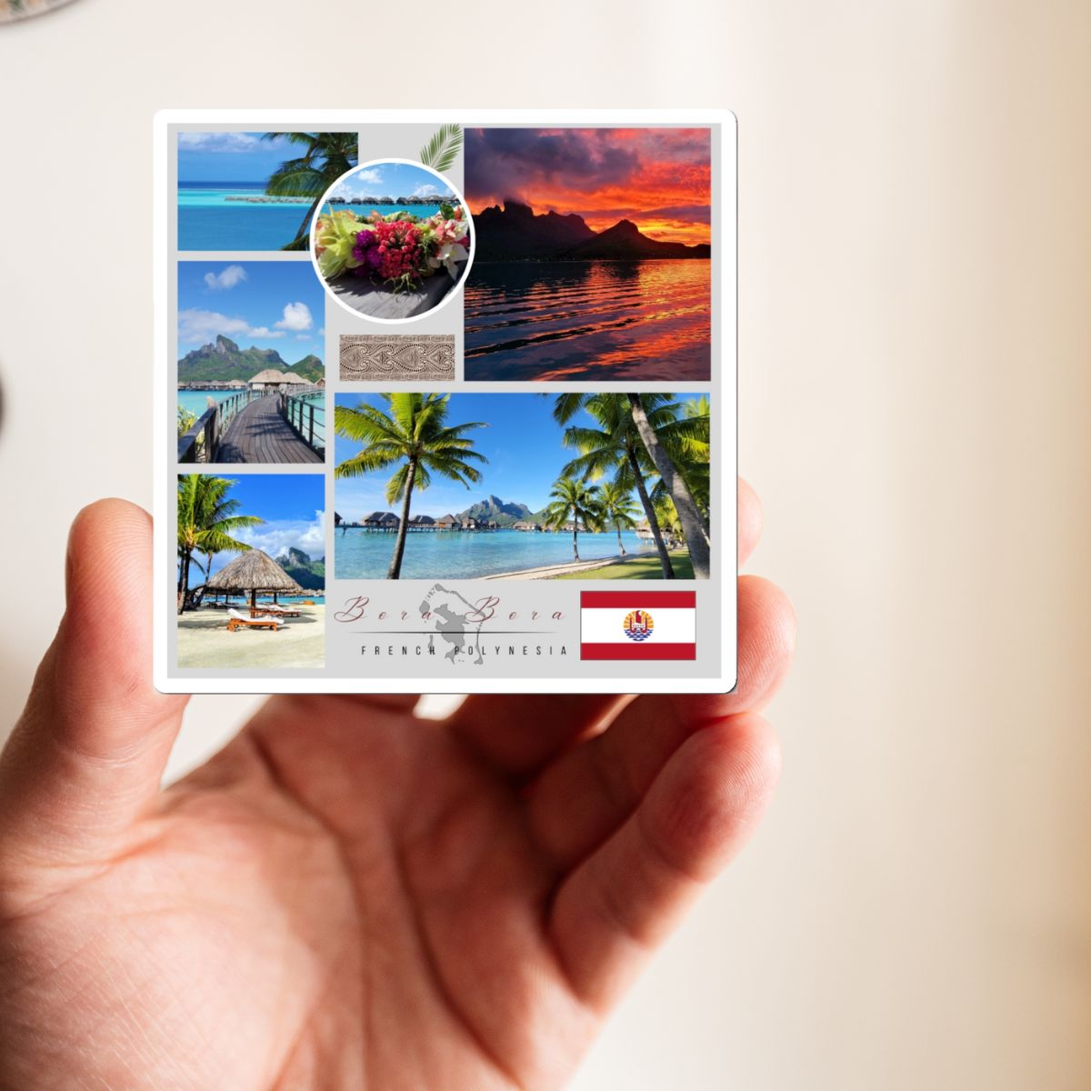 Hand holding a small card with tropical scenery and a flag on a light background