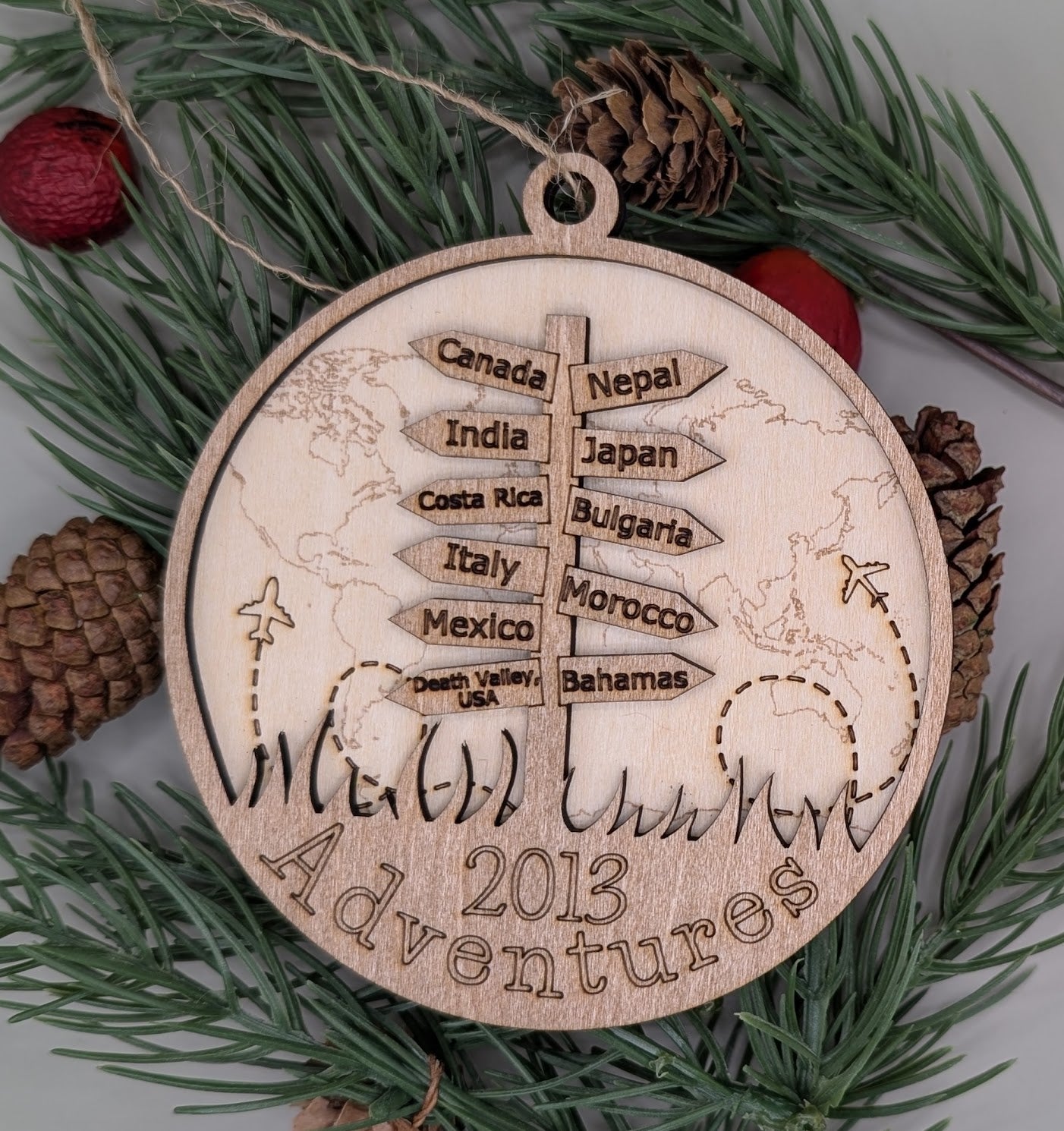 Wooden ornament with world map and travel destinations on a green leaf background