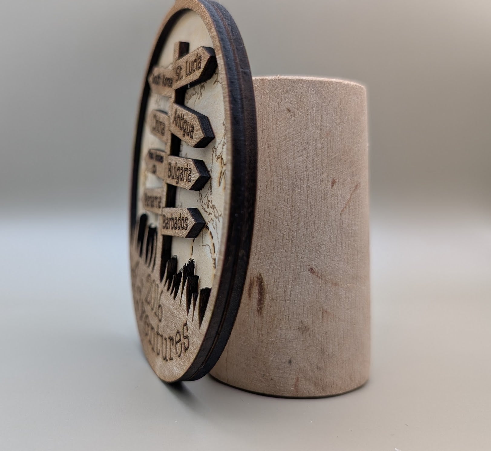 Wooden cylindrical container with a circular wooden sign on a gray background