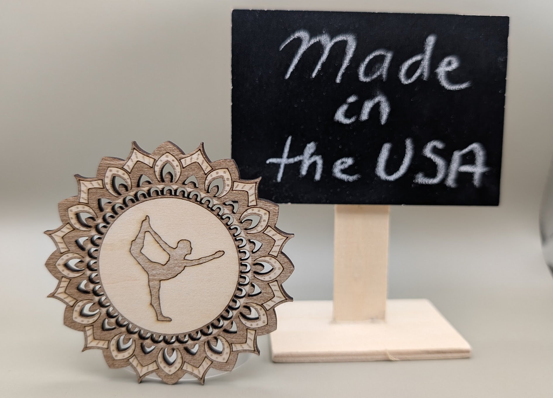 Decorative wooden ornament with a dancer design next to a sign saying 'Made in the USA'.