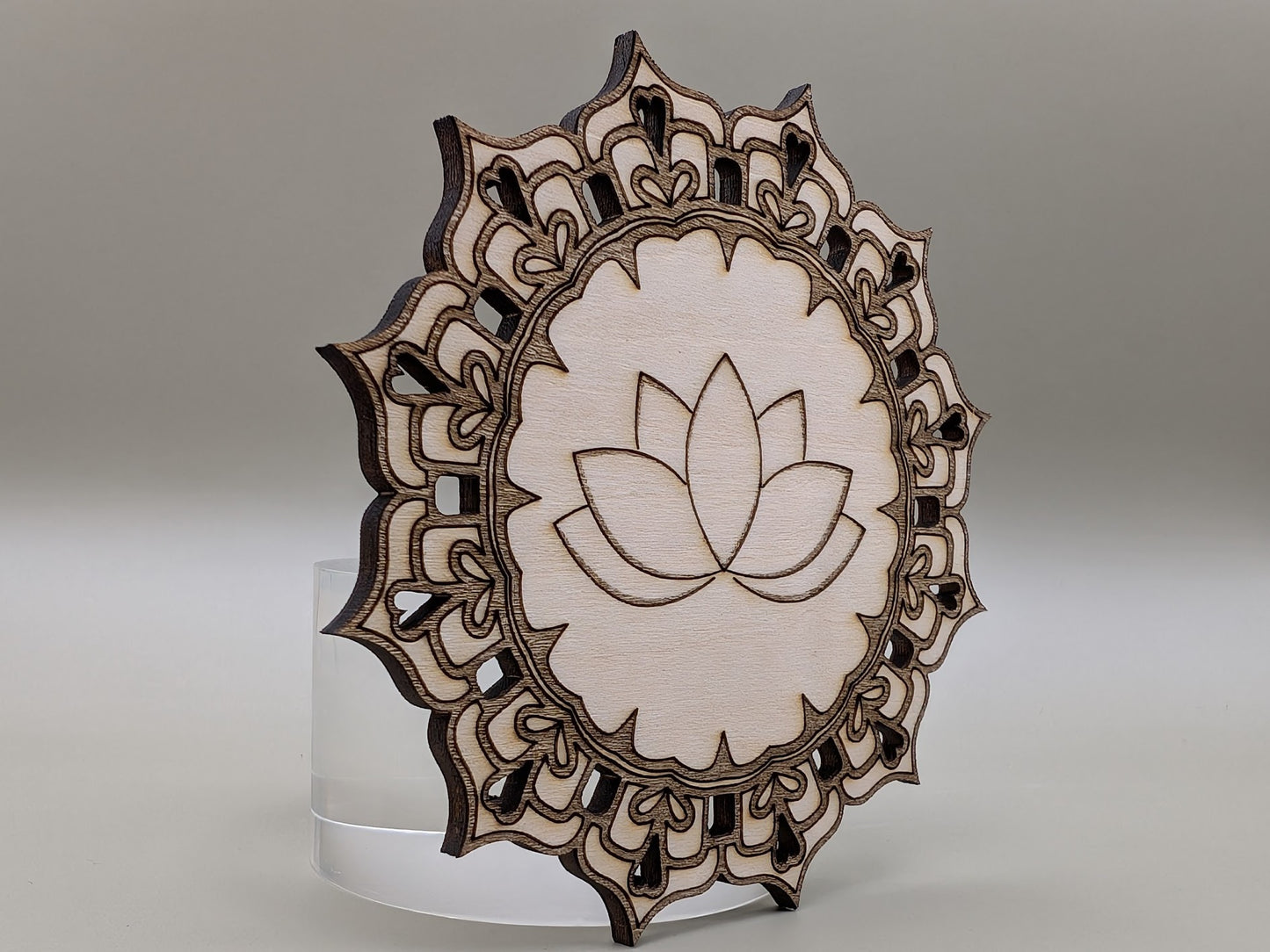 Wooden decorative item with lotus flower design on a gray background