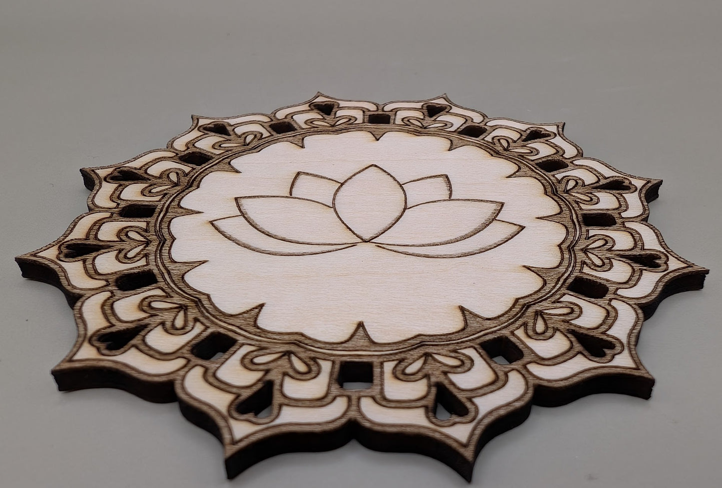 Decorative wooden cutout with lotus flower design on a gray background