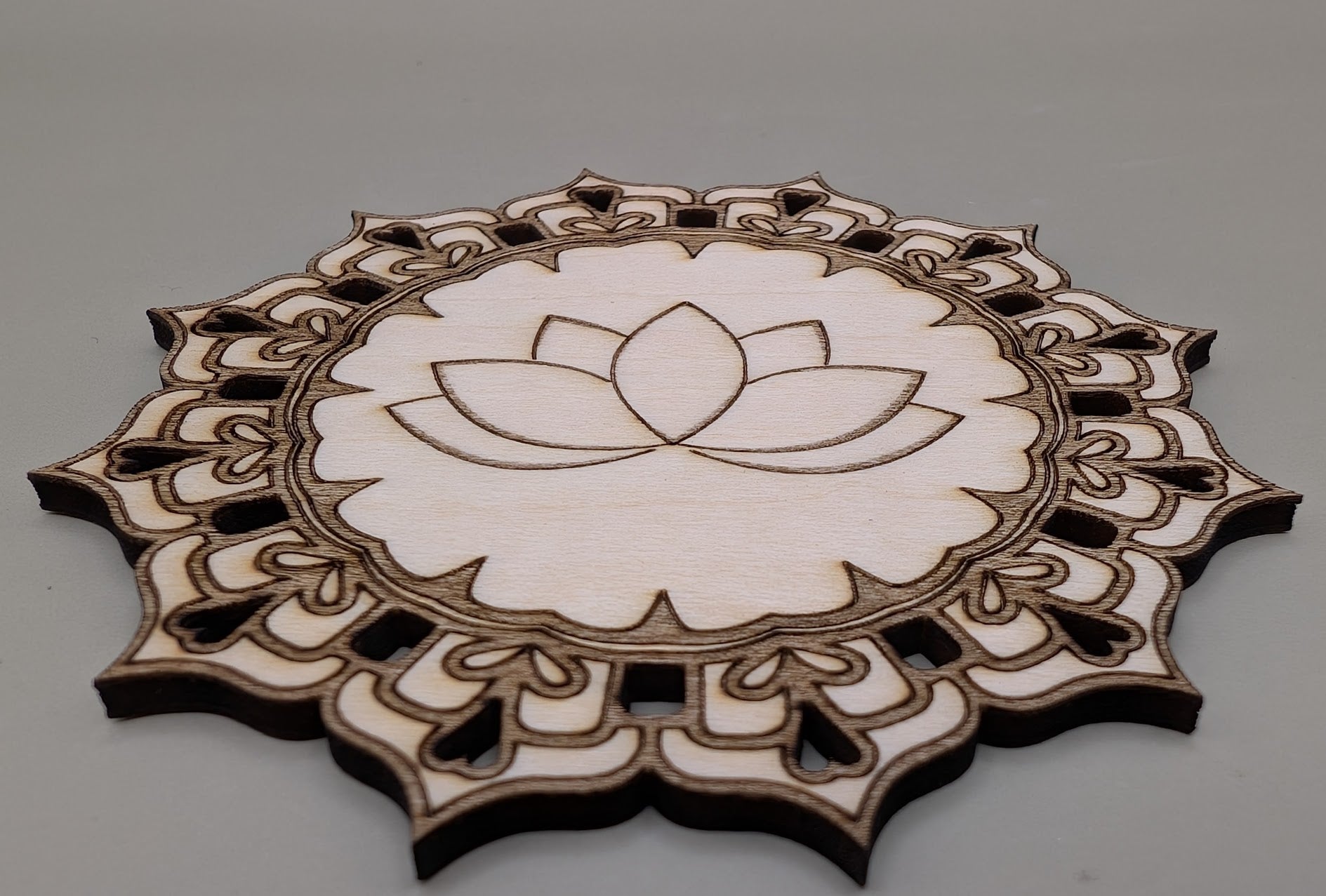 Decorative wooden cutout with lotus flower design on a gray background
