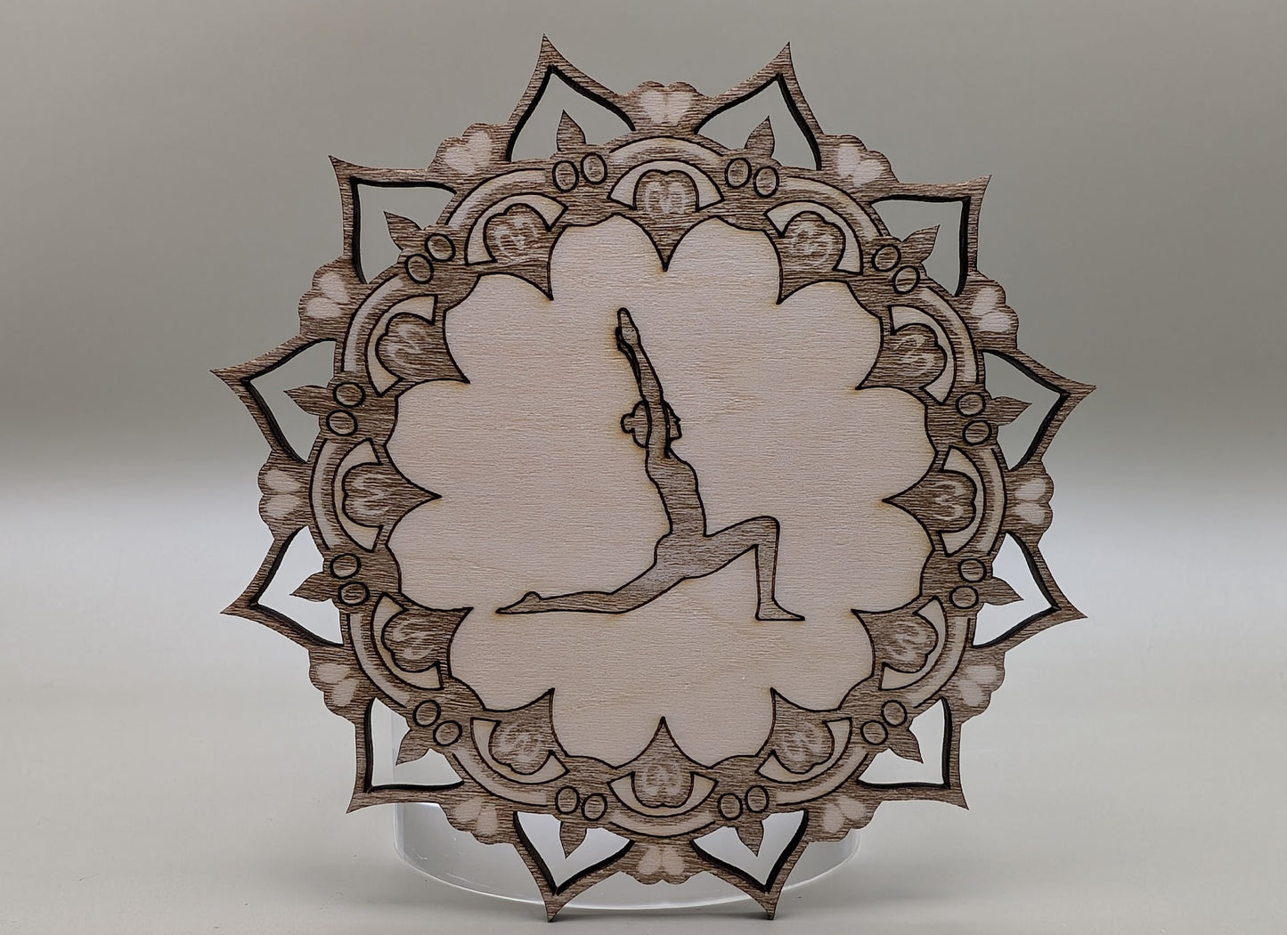 Decorative wooden plate with intricate patterns and a central silhouette on a neutral background