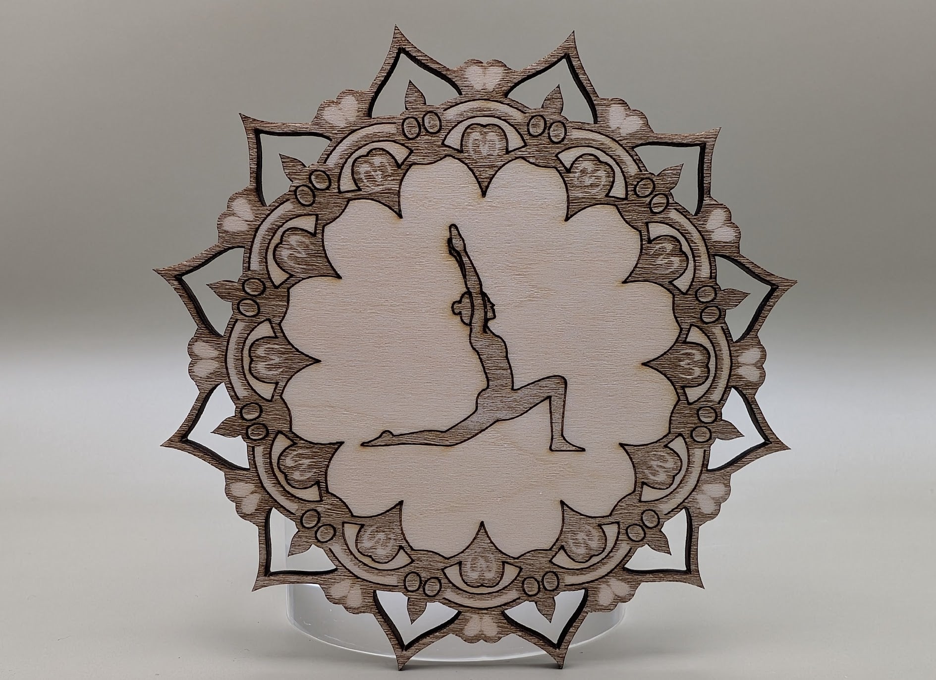 Decorative wooden plate with intricate patterns and a central silhouette on a neutral background