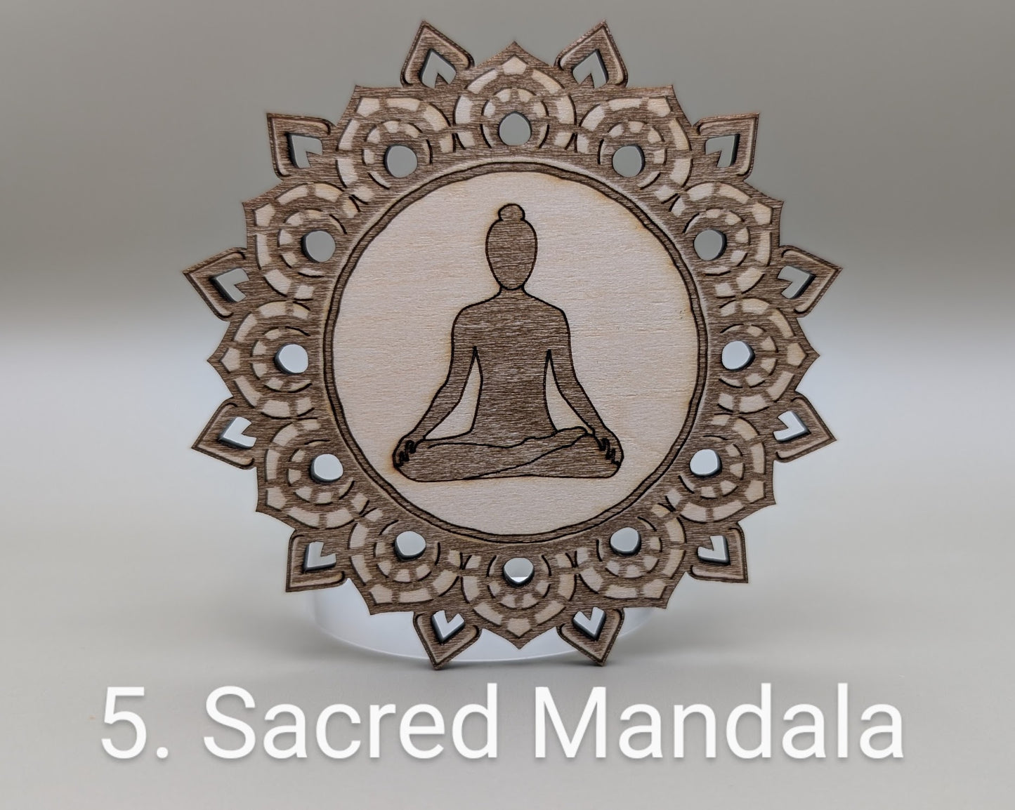 Wooden mandala with a meditating figure in the center on a gray background