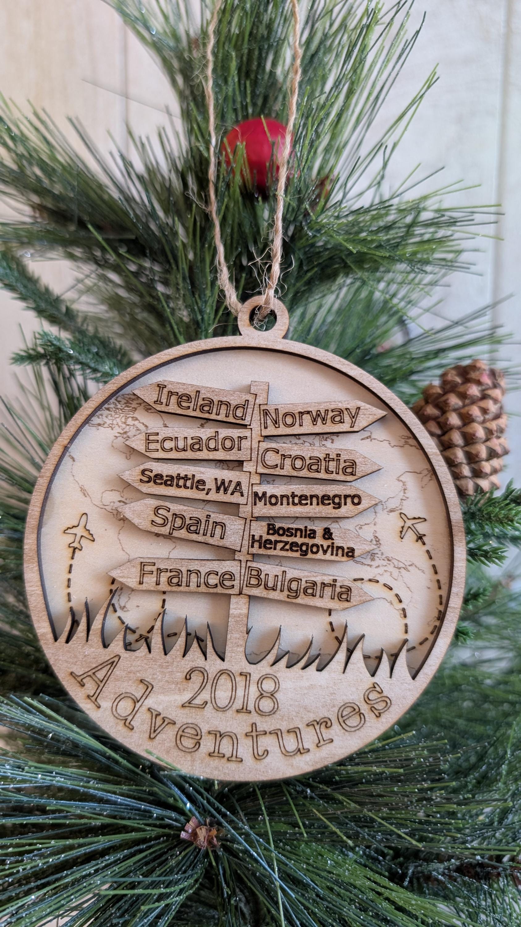 Wooden ornament with engraved travel destinations on a Christmas tree.
