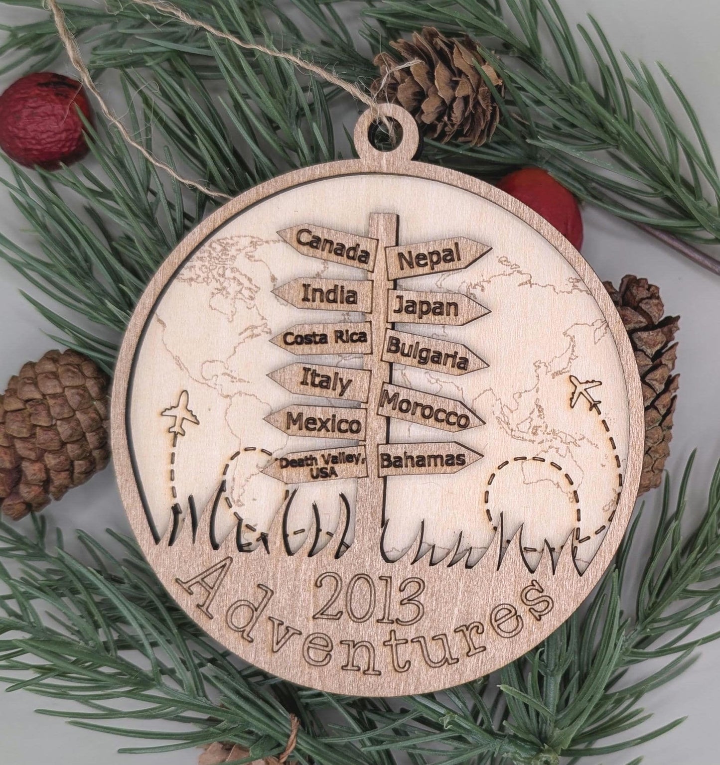 Wooden ornament with world map and travel destinations on a green leaf background