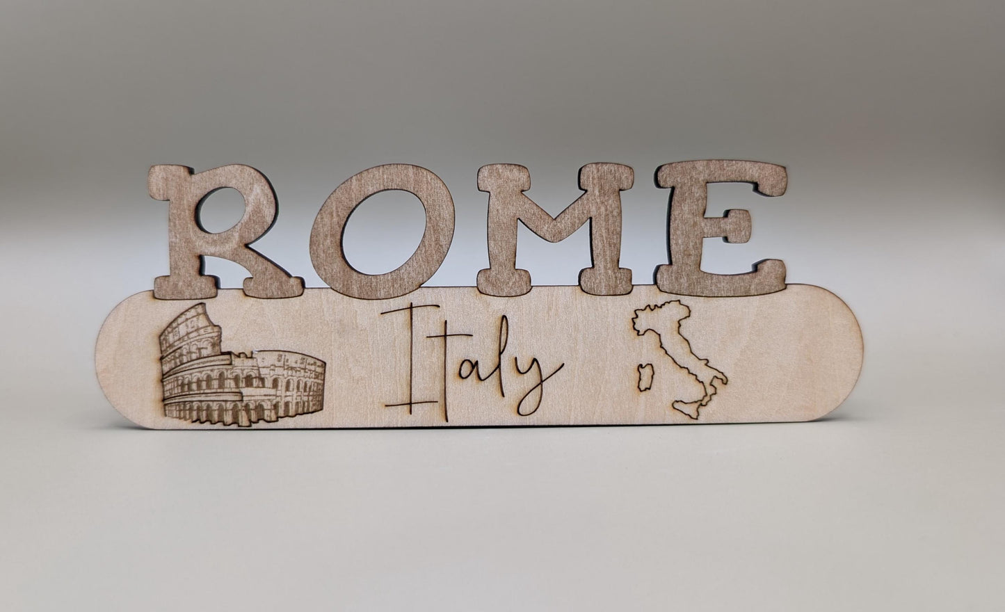 Wooden decorative item with 'ROME Italy' text and Colosseum illustration on a gray background