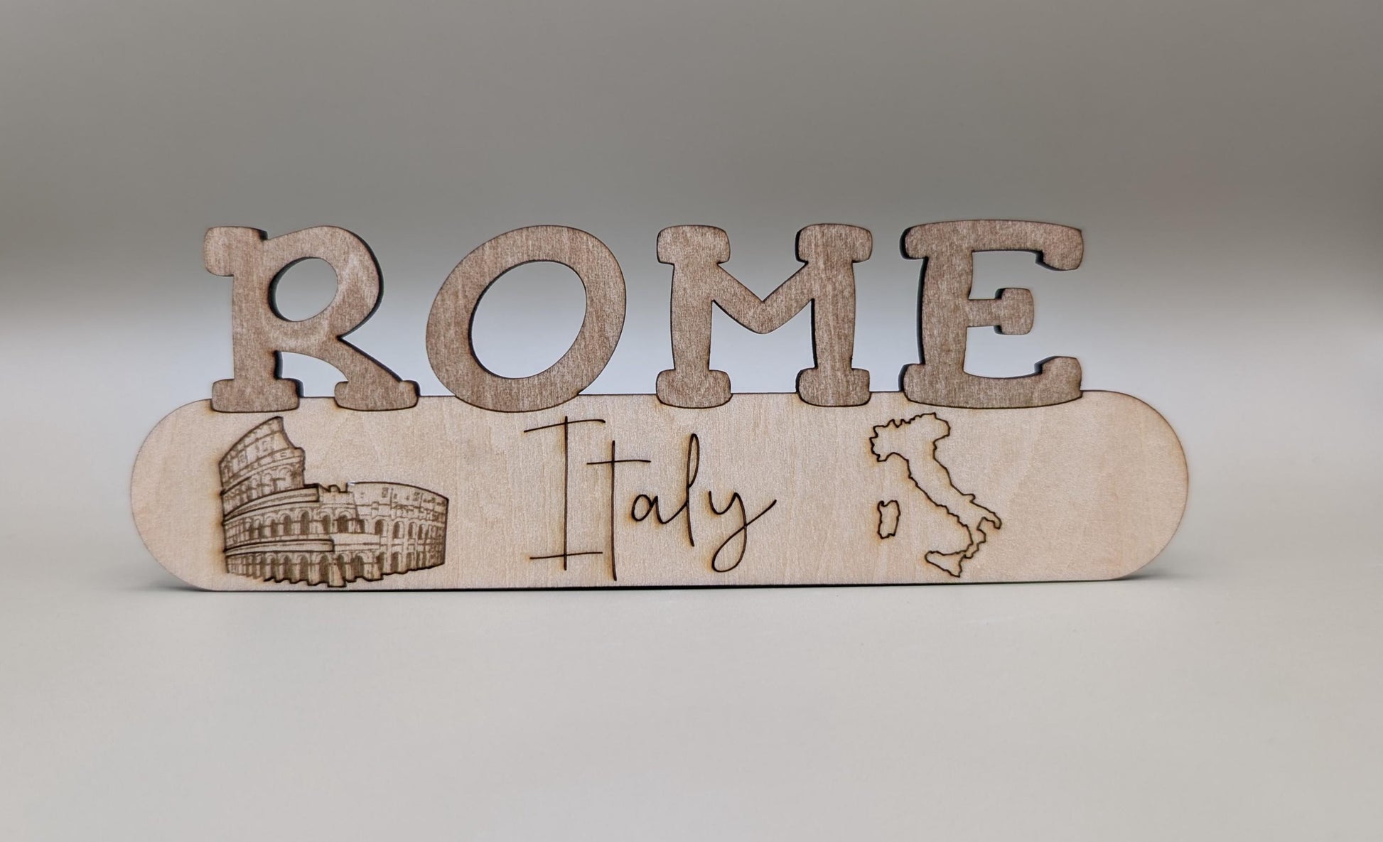 Wooden decorative item with 'ROME Italy' text and Colosseum illustration on a gray background