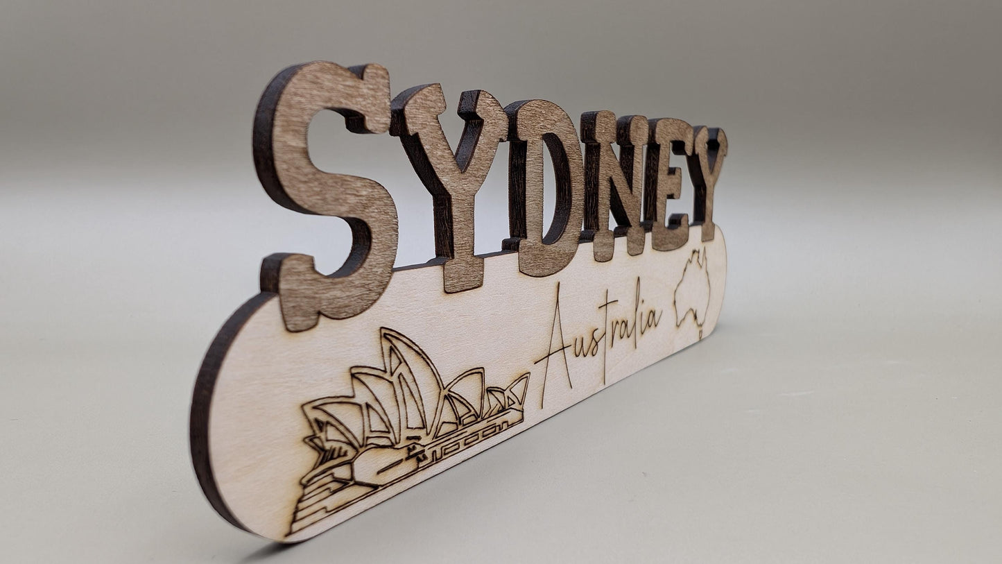 Wooden sign with 'Sydney Australia' text and Opera House illustration on a gray background