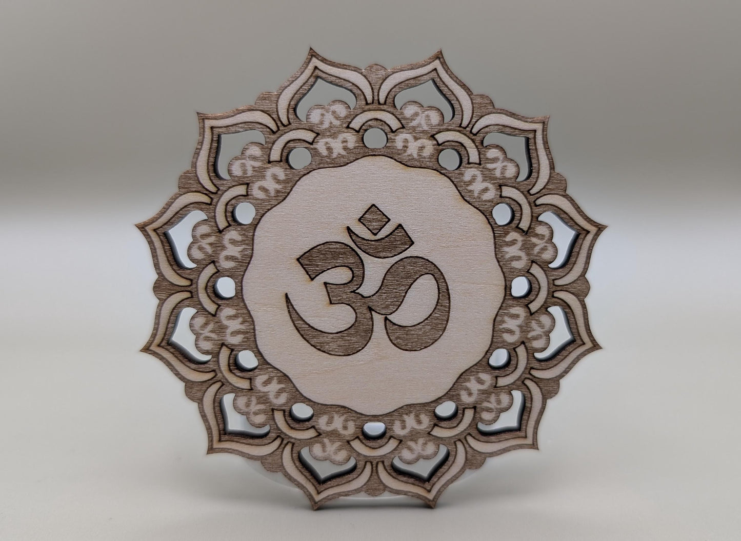 Decorative wooden piece with Om symbol and mandala design on a gray background