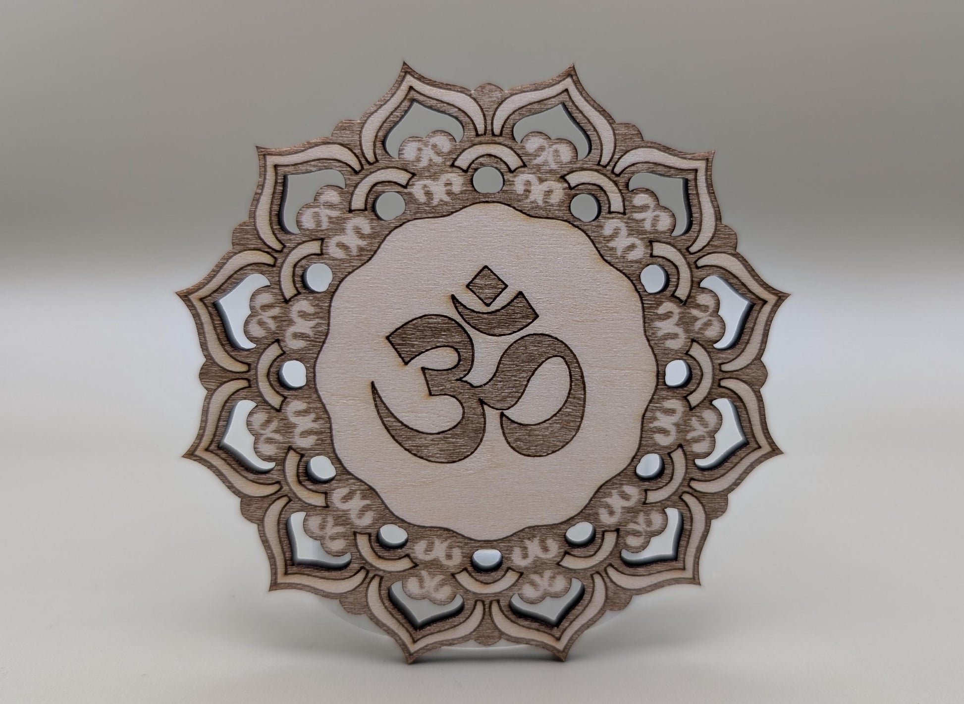 Decorative wooden piece with Om symbol and mandala design on a gray background