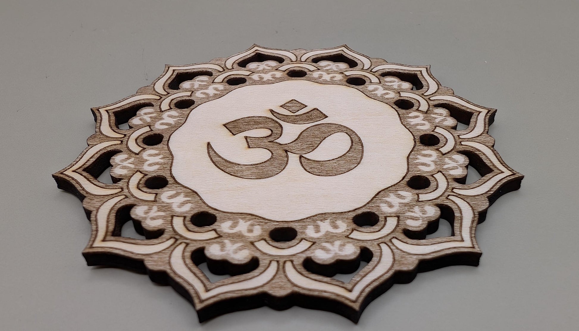 Decorative wooden coaster with Om symbol on a gray background