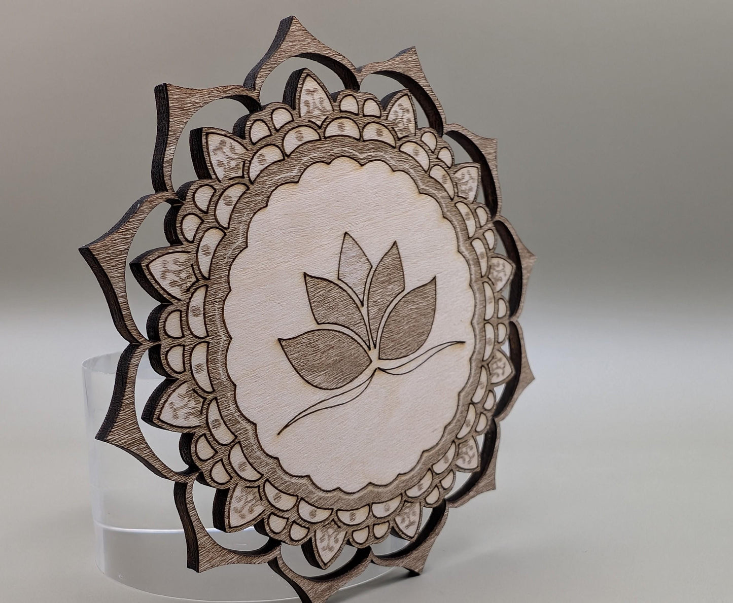 Decorative wooden mandala with leaf design on a gray background