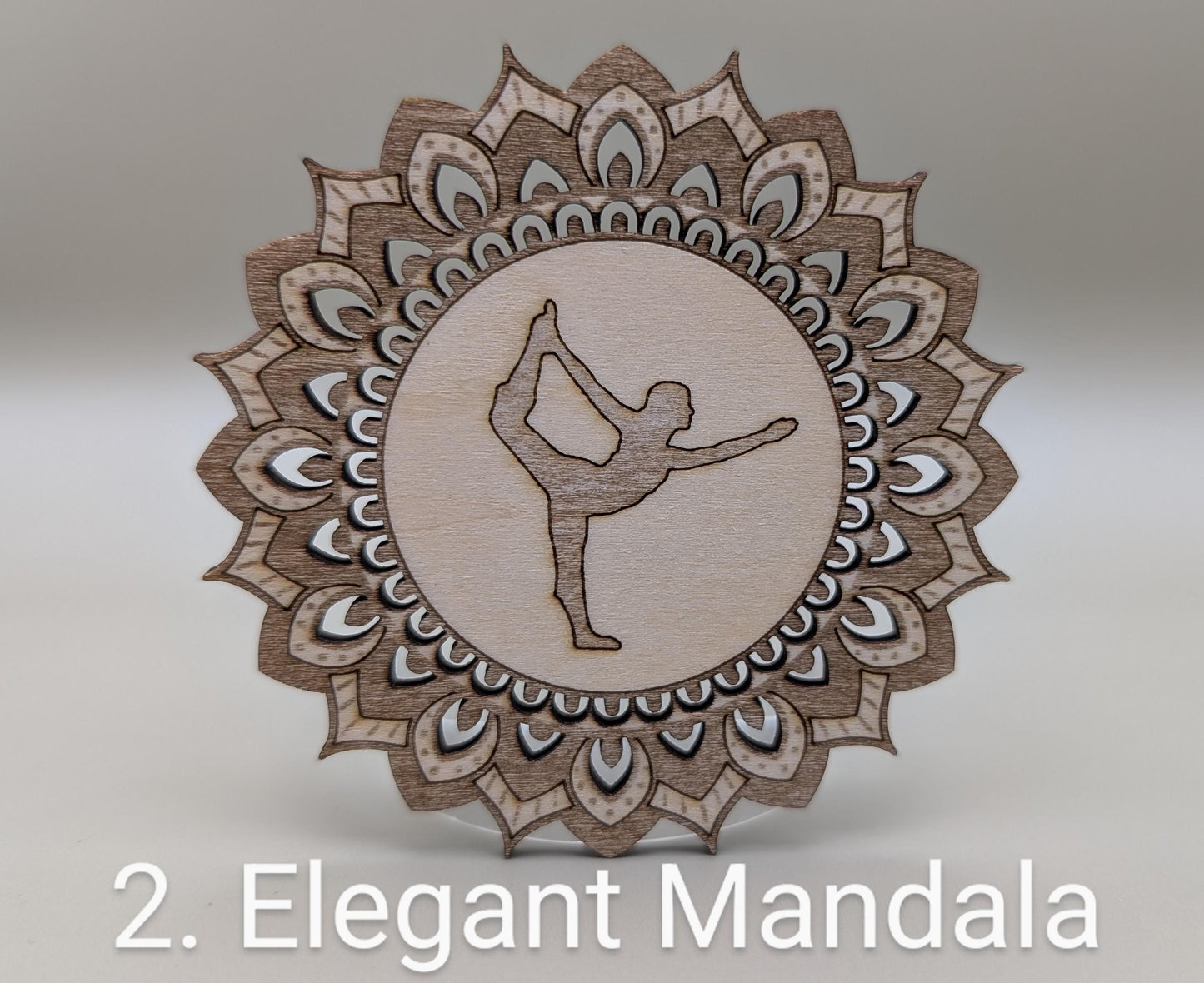 Decorative wooden mandala with a silhouette of a person in a yoga pose on a light gray background.