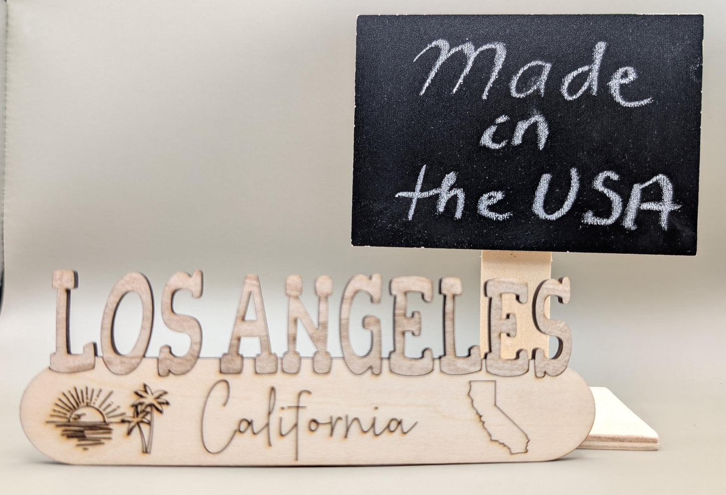 Wooden sign with 'Made in the USA' and 'Los Angeles California' text on a neutral background
