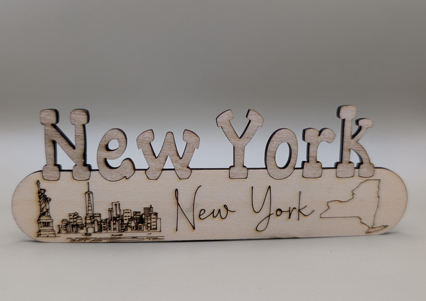 Wooden plaque with 'New York' text and city skyline on a plain background