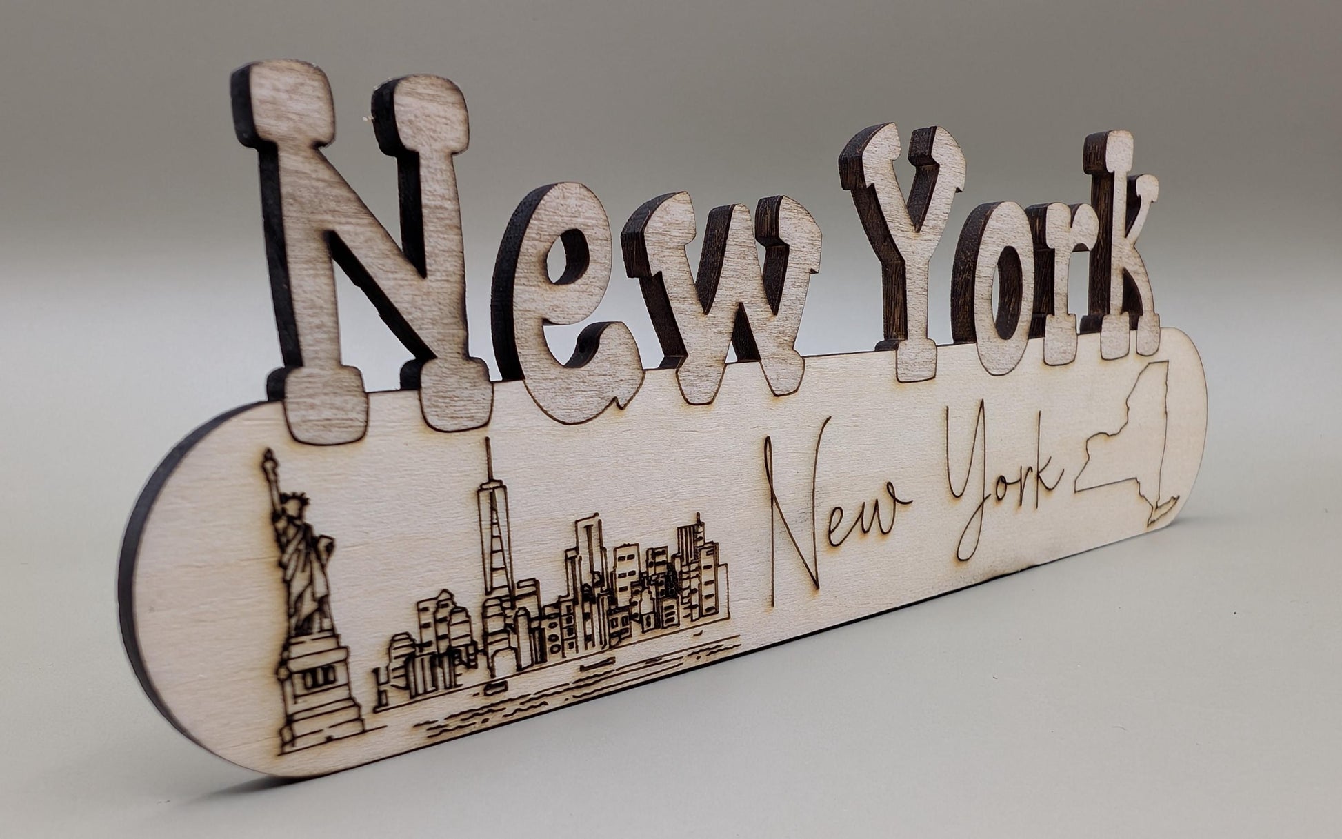 Wooden sign with 'New York' text and skyline illustration on a gray background