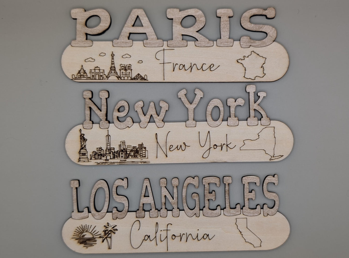 Wooden cutouts with city names and landmarks on a gray background