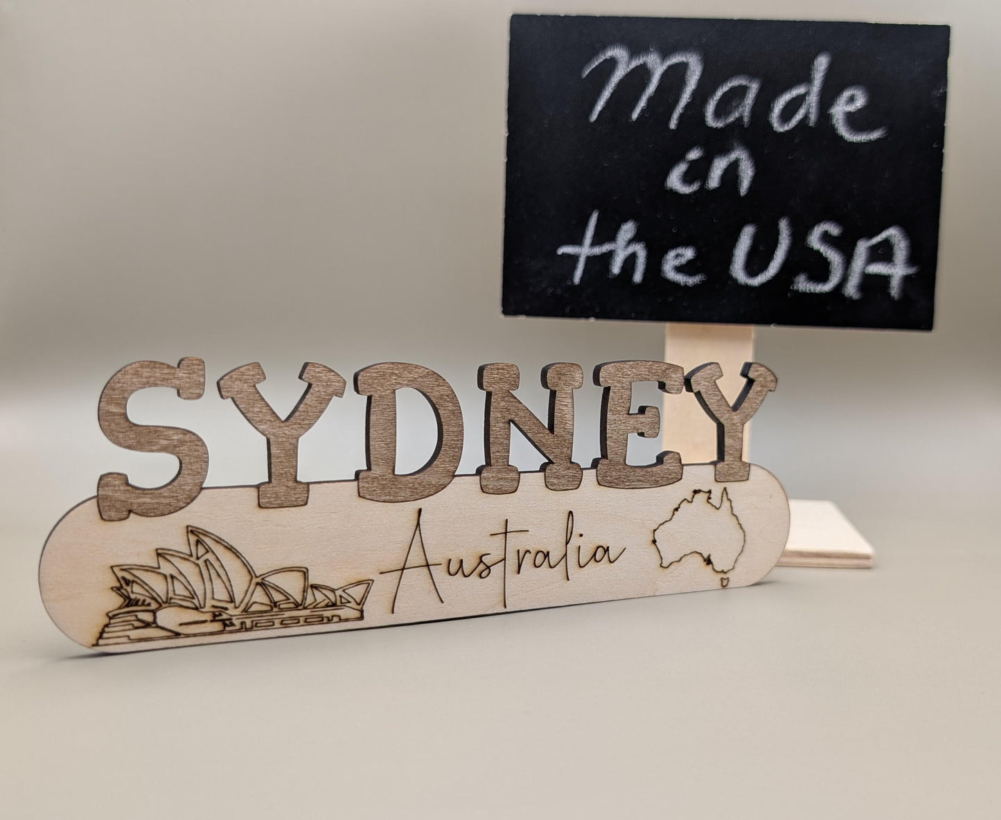 Wooden sign with 'Sydney, Australia' and a small blackboard with 'Made in the USA' text.
