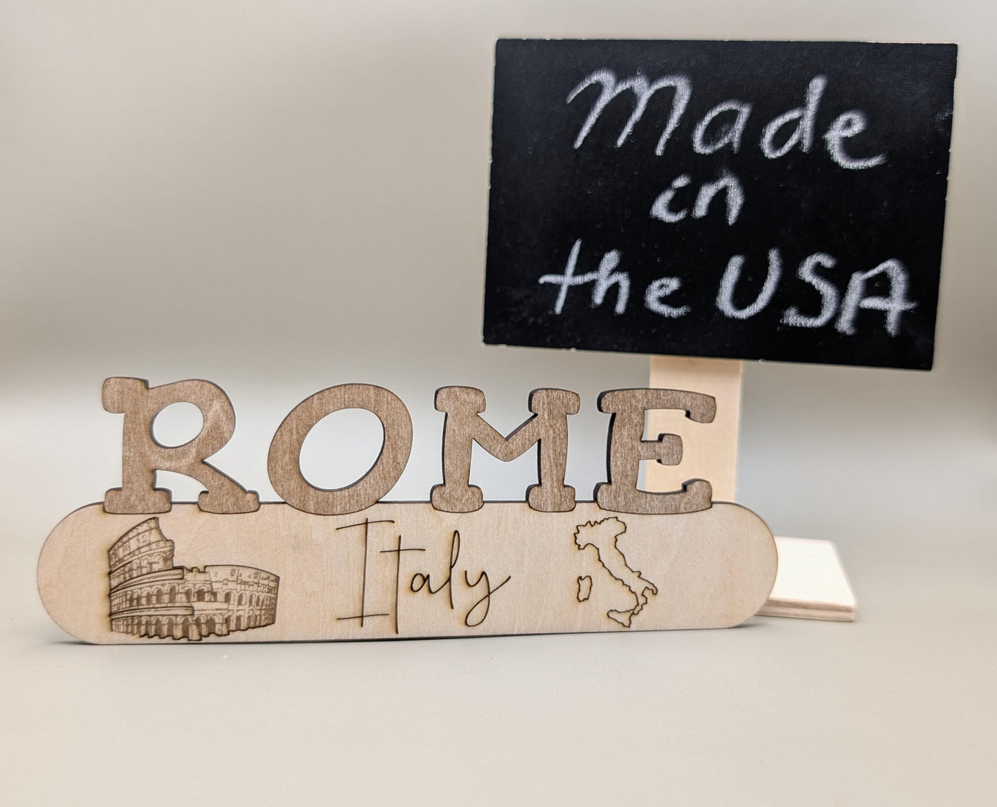 Wooden sign with 'Made in the USA' and 'ROME Italy' text on a neutral background
