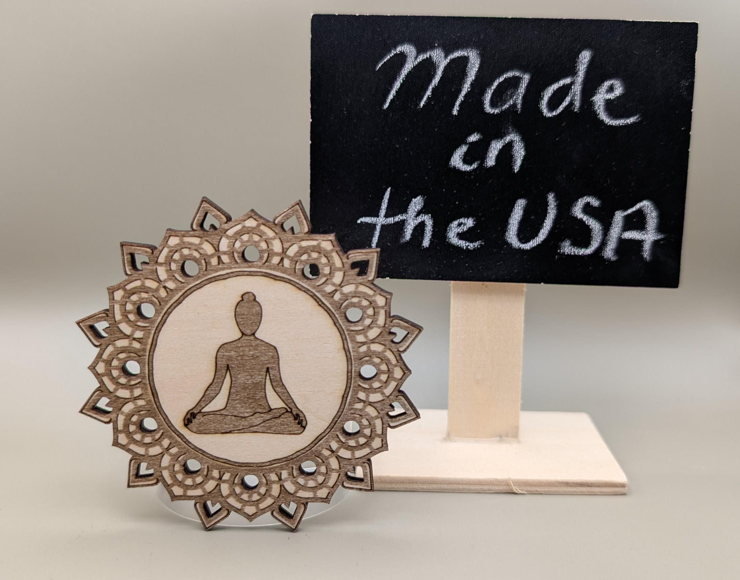 Wooden decorative item with meditating figure and 'Made in the USA' sign